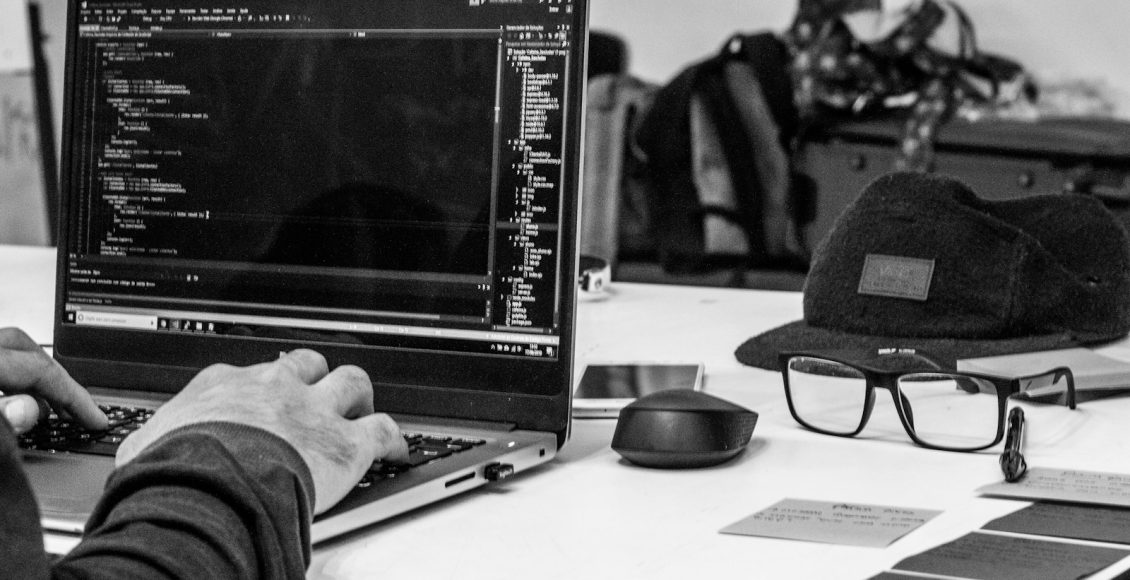 grayscale photo of man using laptop coding