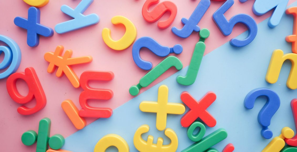 a pile of plastic letters and numbers on a pink and blue background