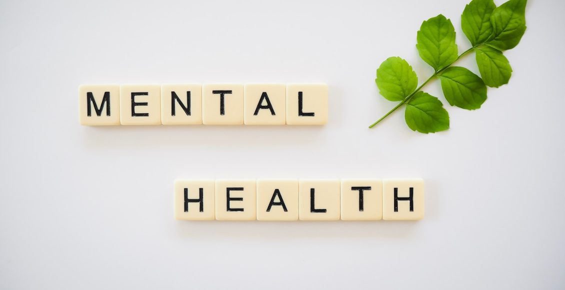 the word mental health spelled with scrabbles next to a green leaf