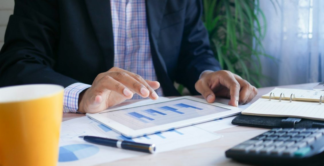person in black suit jacket holding white tablet computer