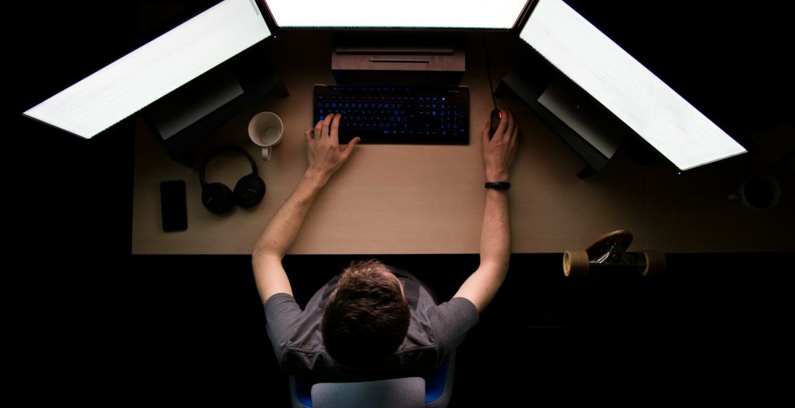 man facing three computer monitors while sitting