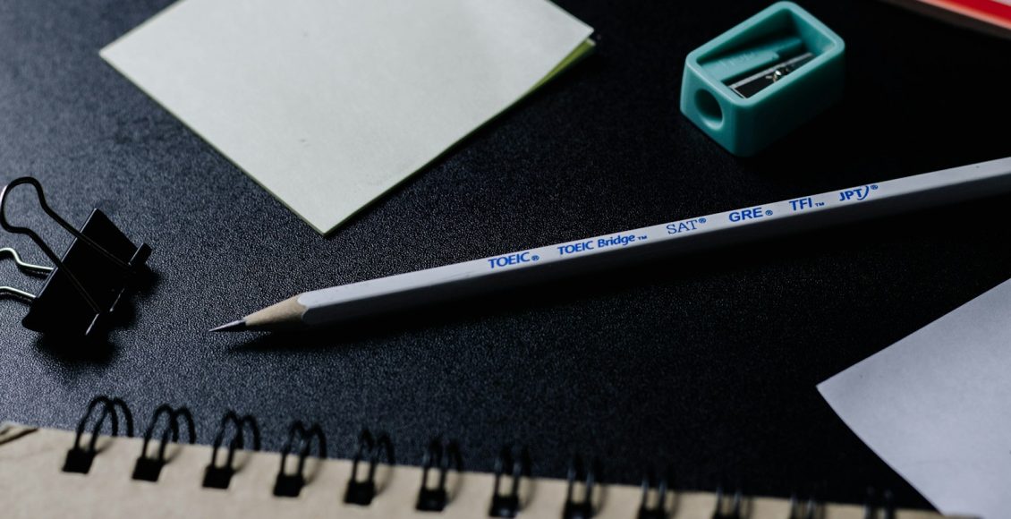 green pencil beside white paper