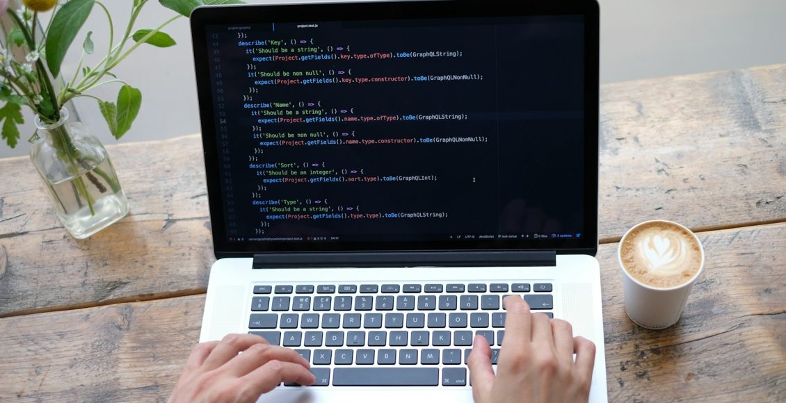 person using macbook pro on brown wooden table