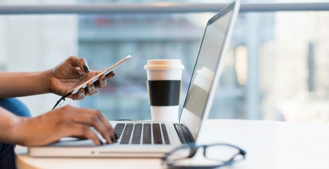 person using smartphone and MacBook